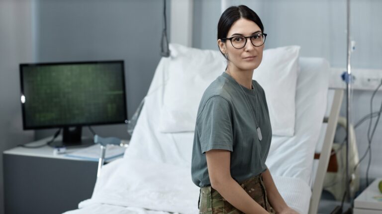 young female soldier in camouflage looking at camera sitting in hospital ward