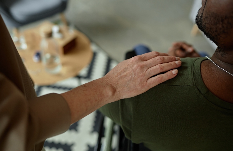 caring female therapist laying hand on shoulder of army veteran