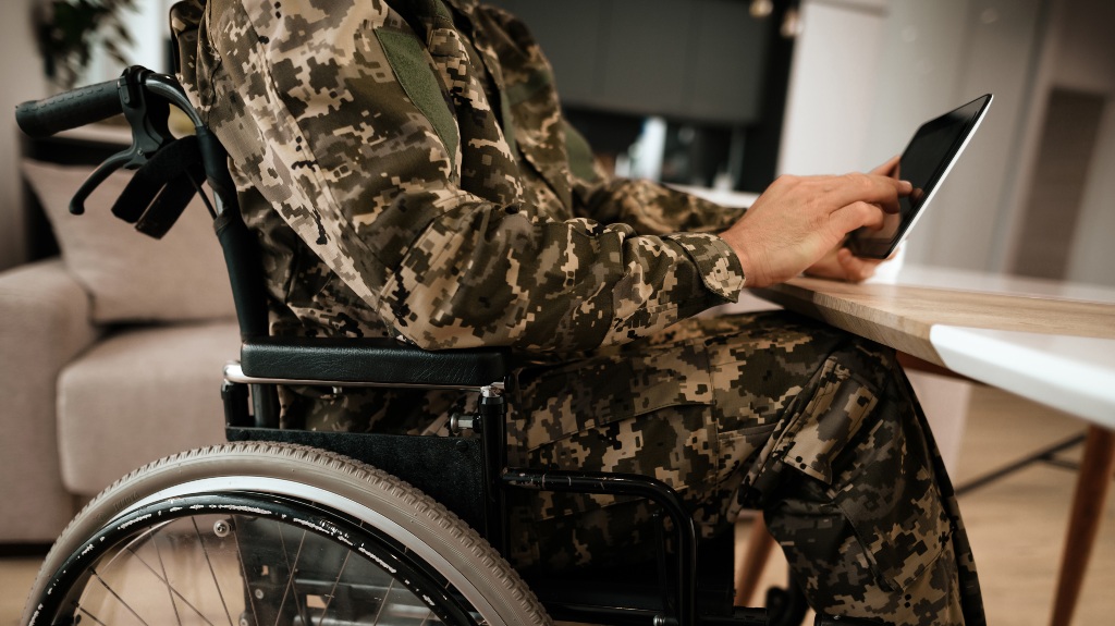 disabled veteran in uniform reading about TDIU on his tablet
