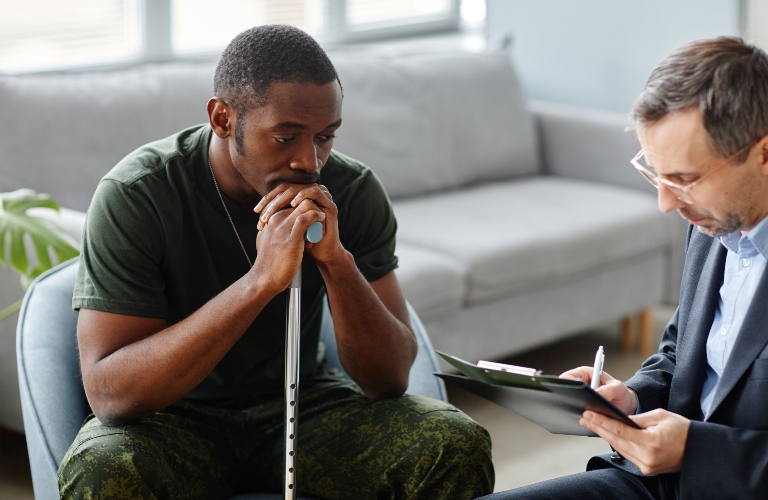 Depressed young adult american soldier with walking stick treating PTSD