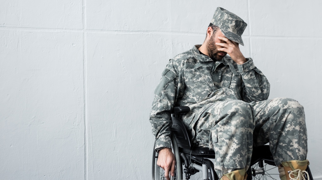 Depressed disabled military man in uniform sitting in wheelchair