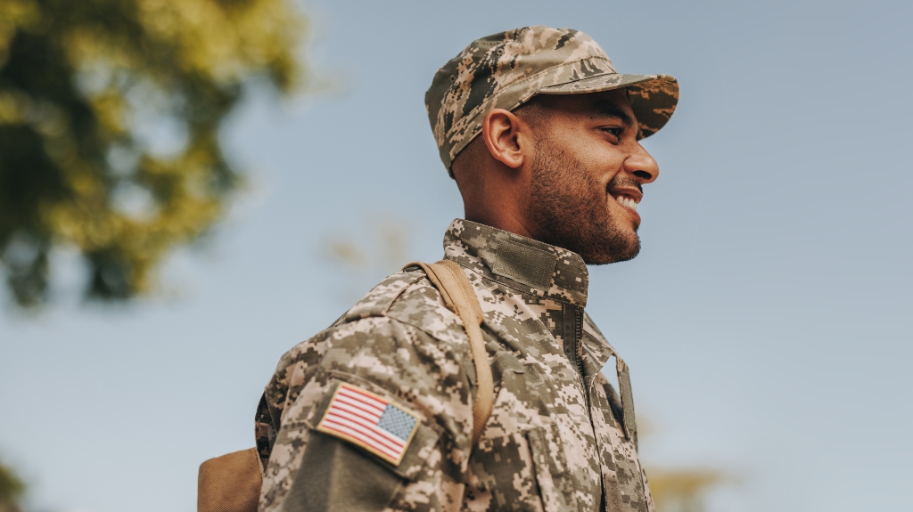 Happy young soldier smiling cheerfully while standing outside his home