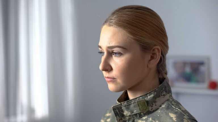 Upset female soldier in military uniform sadly looking